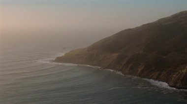 Büyük Sur 'un büyüleyici hava manzarasını tecrübe edin, dramatik uçurumlarını ve günbatımında güçlü okyanus dalgalarını sergiliyor, hepsi California ikonik Karayolu 1' in nefes kesici arka planında geçiyor.