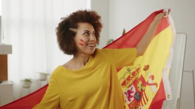 Mutlu İspanyol futbol fanatiği, yanaklarında boyalı bayraklarla favori İspanya takımı için tezahürat yapıyor. Avrupa ve Dünya futbolu, ABD, Fransa, Kanada, Meksika. Spor ve futbol hayranları. Paris Oyunları, Yavaş Hareket