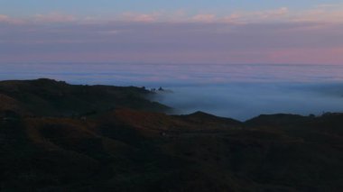 Los Angeles 'taki büyüleyici Malibu dağlarının, gün batımında yemyeşil tepeler ve yumuşak sis ile nefes kesici hava manzarası, unutulmaz bir huzur manzarası yaratıyor.