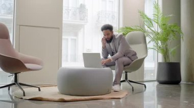 Odaklanmış Afrikalı Amerikalı işadamı, yaratıcılığı ve işbirliğini teşvik eden ilham verici bir çevreyle çevrili modern bir çalışma alanında dizüstü bilgisayarıyla meşgul.