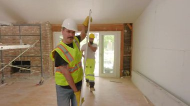 Çeşitli inşaatçılardan oluşan bir ekip, yenilikçi bir yenileme projesi üzerinde, ekipman ve aletlerle dolu, olağanüstü bir ekip çalışması ve adanmışlık sergileyerek işbirliği yapıyor.