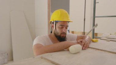 Parlak, düzenli bir çalışma alanında, kendini işine adamış bir inşaat işçisi yorgun, sarsılmaz bir şekilde odaklanma ve her fırça darbesiyle kaliteli işçiliğe olan bağlılığını gösteriyor.