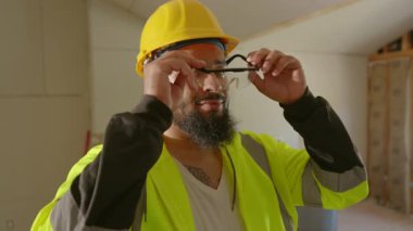 Kendini adamış bir inşaat işçisi koruyucu gözlük ve başlık gibi güvenlik ekipmanları giymenin ve projedeki herkesin iyiliği için yapılan güvenlik uygulamalarını izlemenin önemini vurguluyor.