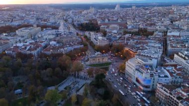 Madrid 'de gün batımında ikonik Puerta de Alcala' nın çarpıcı insansız hava aracı görüntüleri, canlı gökyüzünü aydınlatıyor ve mimariyi ve çevresindeki manzaraları görkemli bir şekilde gösteriyor.