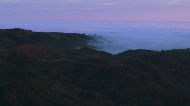 Los Angeles 'taki büyüleyici Malibu dağlarının nefes kesici hava manzarası, özellikle canlı ve renkli bir günbatımında, sisle kaplanmış yemyeşil tepeleri hayrete düşürüyor.