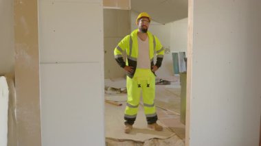 Kendine güvenen bir inşaat işçisi, yüksek görünürlüklü giysiler içinde, inşaat endüstrisindeki mükemmeliyete olan bağlılıklarını, becerilerini ve bağlılıklarını sergileyerek, yoğun bir alanda gururla duruyor.