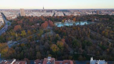 Muhteşem bir El Retiro sonbahar parkını yakalayan nefes kesici görüntülerin tadını çıkarın. Resimli arka planda etkileyici bir şehir siluetinin yanında dingin, pırıl pırıl bir göl de var.