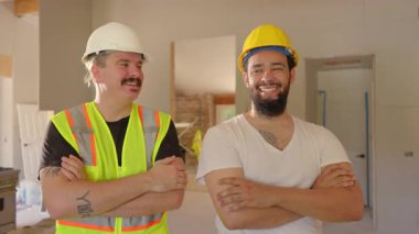 İki neşeli inşaat işçisi hareketli bir iş sahasında birbirleriyle çarpışırken aynı neşeli anı paylaşıyorlar, bu süreçte güçlü takım çalışması ve dostluk hislerini canlı bir şekilde gösteriyorlar.