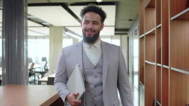 Çağdaş bir çalışma ortamında, iyi giyimli bir Afrikalı Amerikalı işadamı, iş dünyasına dinamik ve yenilikçi bir yaklaşımı somutlaştıran pozitiflik, bencillik ve profesyonellik yayar.