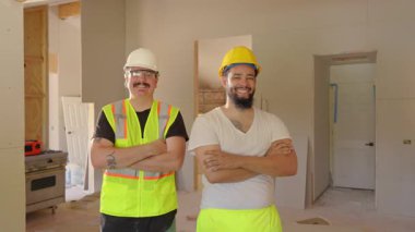 Kaliteli iki inşaat işçisi, inşaat halindeki modern bir binanın önünde dikiliyor ve sektördeki uzmanlıklarını ve profesyonelliklerini sergiliyorlar.