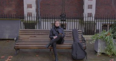 Düşünceli bir müzisyen bir bankta oturuyor, yanında gitar kılıfı tutuyor, gökyüzüne doğru bakıyor, Londra 'da doğanın güzelliği ve sonbahar yapraklarıyla dolu huzurlu, sakin bir açık hava ortamında.