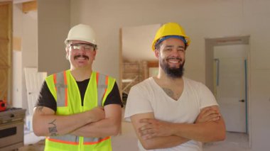 Güvenlik donanımlı iki yetenekli inşaat işçisi, projeyi güvenli ve etkili bir şekilde tamamlamak için çalışırken takım çalışmalarını ve adanmışlıklarını vurgulayarak yoğun bir yenileme sahasında poz veriyorlar.