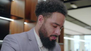 Gösterişli bir sakalı olan hırslı bir Afro-Amerikan işadamı, profesyonellik, bağlılık ve adanmışlık saçan modern bir çalışma alanına odaklanmış durumda.