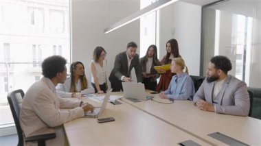 Meşgul şirket bürosu, çeşitli iş adamları finansal analizleri tartışıyor, satış raporlarını gözden geçiriyor, operasyonlarında ve projelerinde başarı için yenilikçi stratejiler geliştiriyorlar.