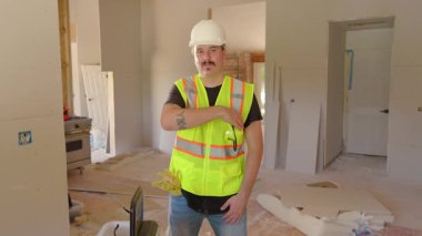 Kendini işine adamış bir inşaat işçisi, daha güvenli bir çalışma ortamı sağlamak için sert şapka ve yansıtıcı yelek giyerek, kendilerini ve diğerlerini risklerden koruyarak güvenliği ön plana çıkarıyor.