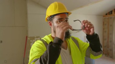 Kendini işine adamış bir inşaat işçisi güvenlik gözlüklerini dikkatlice ayarlar ve hareketli bir bölgede kaskını emniyete alır. Gerekli tüm güvenlik protokollerinin düzgün bir şekilde uygulandığından emin olur.