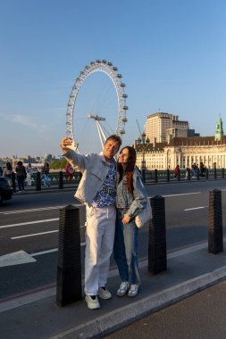 Londra 30.04.2025. Neşeli çift, gün batımında göz kamaştırıcı Londra 'da bir selfie çekiyor. Canlı şehirde hatırlanmaya değer bir aşk ve kahkaha anı yakalıyorlar.