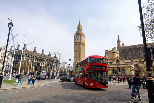 Londra 30.04.2025. Klasik kırmızı çift katlı otobüs Big Ben ve London Eye yakınlarındaki hareketli caddelerde süzülerek şehrin canlı atmosferini ve yerli ve turistlerin günlük yaşamlarını yakalıyor.