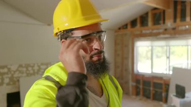 Sıkı bir şapka ve güvenlik gözlüğü takmış kendini işine adamış bir inşaat işçisi, yoğun bir bölgede yenileme planlarını tartışırken, işyeri güvenliği ve yüksek kaliteli standartlara olan bağlılığını vurguladı