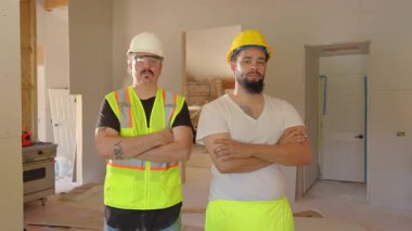 İki inşaat işçisi, her ikisi de parlak güvenlik yelekleri ve sağlam kasklar takan yeni bir inşaat sahasına güvenerek ayakta duruyor. Harekete hazır iyi hazırlanmış bir takımı temsil ediyorlar.