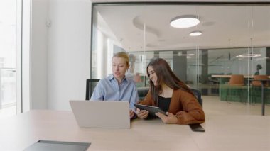 Canlı bir modern ofis ortamında, bir erkek ve kadın profesyonel, iş birliklerini, yaratıcılıklarını ve etkili iletişimlerini geliştirmek için bir dizüstü bilgisayar kullanarak verimli bir tartışmaya girişirler.