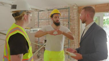 Yetenekli çeşitli inşaat ekibi yenilenmiş bir alanda önemli proje ayrıntılarını tartışıyor. Herhangi bir projenin başarısı için etkili bir işbirliği ve planlama şarttır.