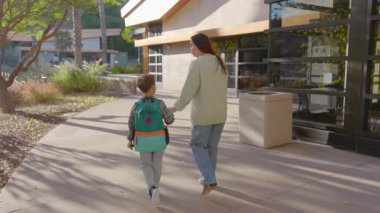 Bu yürek ısıtan anda, sevgi dolu bir ebeveyn ve meraklı çocuğu okula doğru neşeyle el ele yürür, güzel bir şekilde aralarındaki sevgi ve arkadaşlık bağını gösterirler.