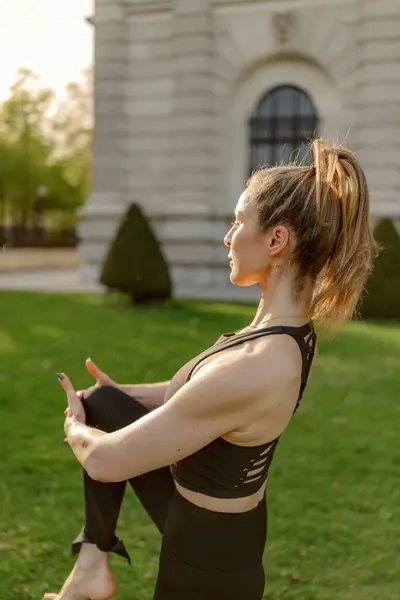 Genç bir kadın dışarıda yoga yapıyor, esnekliğini ve sükunetini, çarpıcı ve resim gibi doğal bir zemine karşı ustalıkla sergiliyor, çevresindeki çevreyle uyum içinde.