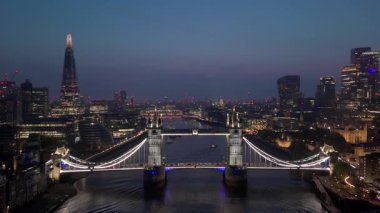 Nefes kesen hava manzarası Londra 'nın ikonik Tower Köprüsü' nü, alacakaranlıkta güzelce aydınlatılarak Thames nehri boyunca uzanan canlı ve dinamik Londra siluetini aydınlatıyor. İngiltere