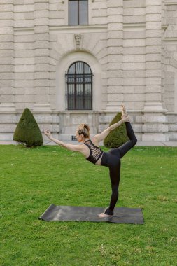 Tarihi bir arka planla birlikte, güzel manzaralı bir dış mekanda, orta yaşlı bir kadın yoga yaparken görülüyor, bu sakin ve huzurlu sahnede inanılmaz bir odak ve denge sergiliyor.