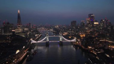 Hava aracı Londra 'daki ikonik Tower Köprüsü' nü ve alacakaranlıkta canlı Londra siluetini yakalar. Thames Nehri 'nin sakin sularına yansıyarak İngiltere' nin başkentinde nefes kesici bir manzara yaratır.