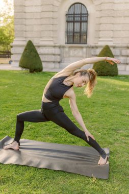 Orta yaşlı bir kadın sakin ve güzel bir ortamda yoga yapıyor. Etkileyici esnekliğini ve derin sakinliğini gösteriyor.