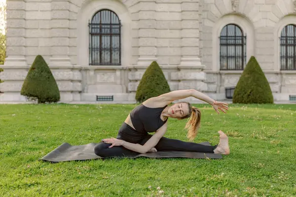 Midadlı bir kadın, doğa güzelliğinin ortasında güzel ve zarif bir duruş sergilerken, esnekliğini ve farkındalığını büyük ölçüde artıran çarpıcı bir ortamda yoga yapıyor.