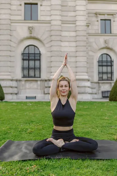 Midadlı bir kadın, doğa ve temiz havanın güzelliği ve güzelliği ile çevrili iken, dinginlik, sağlık ve farkındalık kavramlarını mükemmel bir şekilde gösteren, çarpıcı bir açık havada yoga yapıyor.