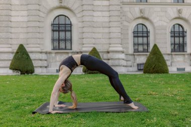 Genç bir kadın serinletici havada karmaşık bir yoga pozisyonu sergiliyor, inanılmaz esnekliğini ve derin bir dinginlik duygusunu sergiliyor nefes kesici güzellikte yankılanıyor.