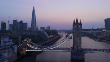 Hava görüntülerinde Tower Köprüsü ve Londra alacakaranlıkta ufuk çizgisine vurgu yapılıyor. Thames nehri canlı şehir ışıklarını yansıtıyor ve şehir yaşamını çeken büyüleyici bir manzara yaratıyor.