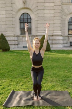 Sakin bir açık hava ortamında, orta yaşlı bir kadın yoga yapıyor, dengesini ve gücünü gösteriyor. Sakin ortam egzersiz deneyimini güçlendiriyor, zihinsel beden bağlantısını derinleştiriyor.