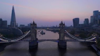 Tower Köprüsü 'nün ve alacakaranlıkta Londra ufkunun nefes kesici hava manzarasının tadını çıkarın. Thames Nehri' nin durgun ve pitoresk bir atmosfer yaratarak parıldayan yansımaları ile.
