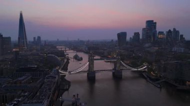 Dramatik insansız hava aracı görüntüleri Londonların alacakaranlık siluetini gösteriyor, ikonik Tower Köprüsü ve parıldayan Thames Nehri 'nin yer aldığı, izleyicileri büyüleyen büyüleyici bir alacakaranlık sahnesi yaratıyor.