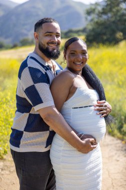 Afrika kökenli Amerikalı bir çift dışarıda güzel bir yaz gününün tadını çıkarıyor, neşeli hamilelik beklentilerini kucaklıyor ve bu hayret verici doğal ortamda geleceklerini iple çekiyorlar.
