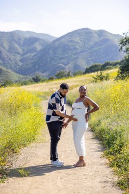 Güneşli güzel bir günde, neşeli bir çift ebeveynliğe doğru heyecanlı yolculuklarını kucaklıyor, yeni değerli bebeklerinin gelişini sabırsızlıkla beklerken derin sevgilerini ve heyecanlarını sergiliyorlar.