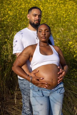 Neşeli ve enerjik bir Afro-Amerikan çifti güzel güneşli bir günün tadını çıkarıyor, hamileliklerini ve doğanın güzelliği arasında büyüyen ailelerinin harika yolculuğunu kutluyorlar.