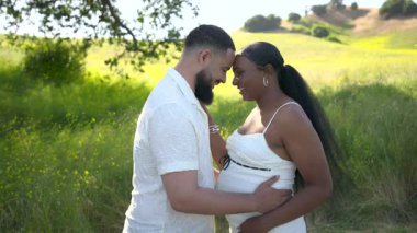 Doğanın güzelliğinin ortasında, yeni bebeklerini bekleyen neşeli bir çift, sevgisini kucaklamak ve sıcak, ışıl ışıl yaz güneşinin altında ebeveynliğin heyecanını tatmak için bir dakikalarını ayırıyor.