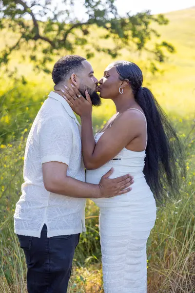 Çok sevecen bir Afrikalı Amerikalı çift açık havada güneşli bir günün tadını çıkarıyor ve el üstünde tutuyor. Birbirlerini kucaklıyor ve doğanın güzelliği arasında beklenen beklentilerini neşeyle kutluyorlar.