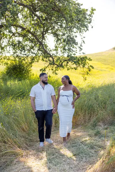 Afrika kökenli Amerikalı bir çift, doğadaki hamileliklerini sevinçle kutluyor. Yazları bir ağacın altında sıcaklığı kucaklıyor ve bu özel zamanı gelecekteki aileleri için sevgi ve beklentiyle kutluyorlar.