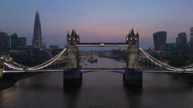 Havadan çekilmiş bir alacakaranlık fotoğrafı Tower Bridge Londra 'nın ufuk çizgisini aydınlatıyor, yansıması Thames nehrinde dans ediyor, bu büyüleyici gecede unutulmaz bir atmosfer yaratıyor.