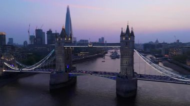 Bu çarpıcı hava görüntüsü ikonik Tower Köprüsü 'nü, alacakaranlıkta güzel Londra silueti ile birlikte, Thames Nehri' nin sakin sularını incelikle yansıtıyor.