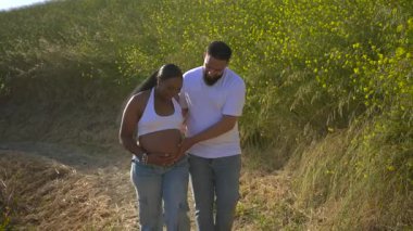Afrika kökenli Amerikalı bir çift, doğada sakin bir yaz gününün tadını çıkarıyor, yeşilliklerle çevrili, bebeklerinin gelişine ve ebeveynliğe yeni yolculuklarına hazırlanırken mutlu anlar yaşıyorlar.