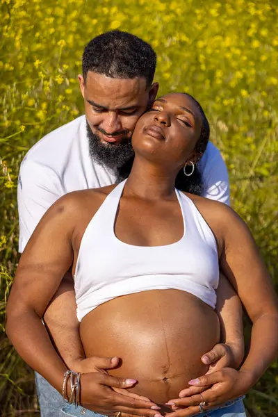 Afrika kökenli Amerikalı bir çift dışarıda hamileliklerini sevinçle kutluyor. Koca, eşlerine kucak açıyor. Yeşillik içinde, büyüyen aileleri için heyecanlı bir ortam yaratıyor.