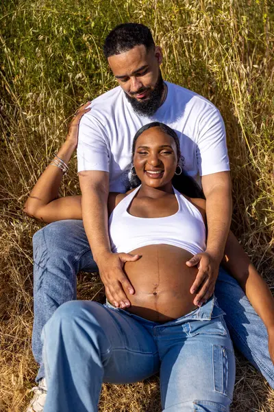 Güneşli bir yaz gününde, Afrikalı Amerikalı bir çift dışarıda neşeyle kucaklaşır, koca, karısına sevgiyle sarılır ve bebeklerinin gelişini kutlar.